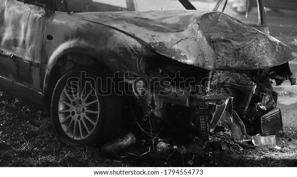 Front view of\
the car burned after the serious car accident at night in winter.\
Black and white. High quality\
photo