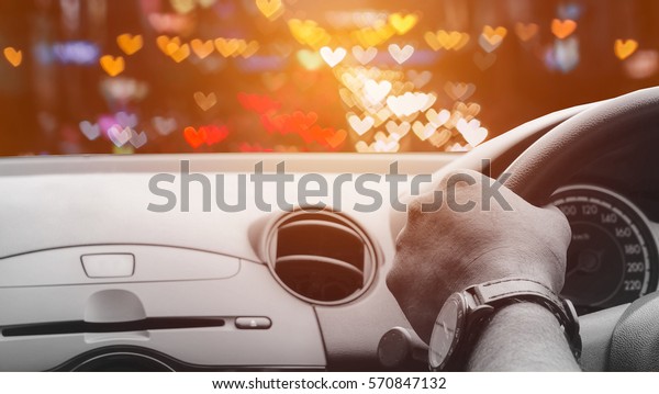 Front view of car looking out from\
inside with bokeh heart shape traffic on road\
background