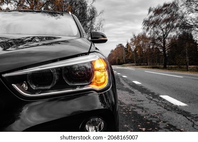 Front View Of A Car On The Road Starting To Move After Stopping And The Left Turn Light On.