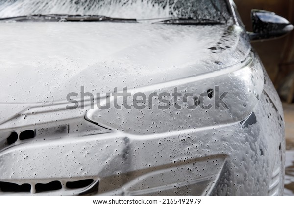 Front\
view of car with  washing foam, and soap on hood\
