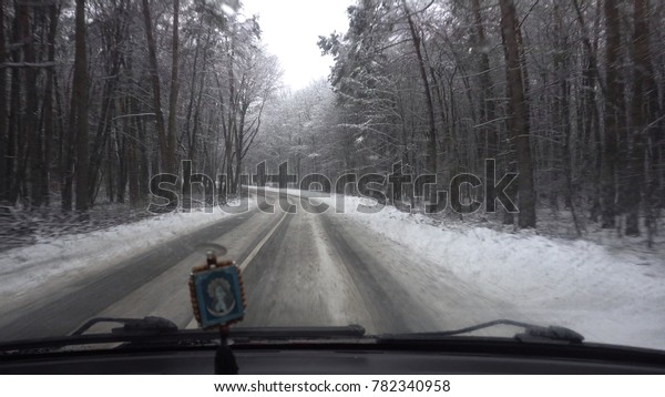 Front view from car when vehicle driving winter\
snowy forest road.