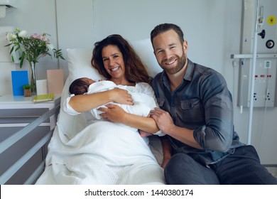 Front View Of Caucasian Couple Holding Their Newborn Baby In The Ward At Hospital