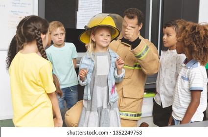 Front view of a Caucasian firefighter teaching to schoolkids about fire safety in classroom at school - Powered by Shutterstock