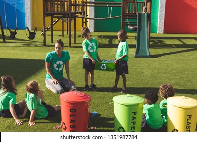 Front view of caucasian teacher discussing about green energy and recycle with students while txo students holding a filled box in playground at schoolyard  - Powered by Shutterstock