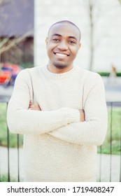 Front view of cheerful guy standing and looking at camera. Smiling African American man with crossed arms posing outdoors. Citizen concept