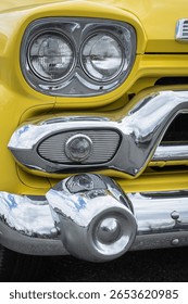 Front view close up of a headlight of antique vehicle. The headlamp and grill on an old yellow car. Headlight lamp vintage classic car. Retro classic car. Street photo, nobody