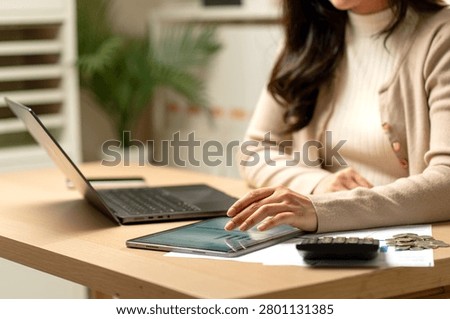 Front view close up left hand of woman touch and work with tablet near calculator, laptop and coins on table in concept of new technology to support the success of business.