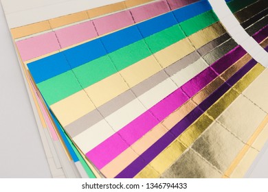 front view close up of multicolor color stamping hotfoil paper spectrum sampler isolated on white background - Shutterstock ID 1346794433