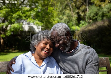 Front view close up of senior African American couple in the garden,  sitting on a bench, embracing and smiling. Family enjoying time at home, lifestyle concept