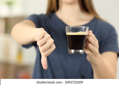 Front view close up of a woman hands holding a coffee cup with thumbs down at home