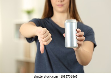 Front view close up of a woman hands holding a soda drink can with thumbs down at home