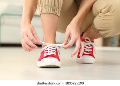 Front View Close Up Of Woman Tying Shoelaces Of Sneakers On The Floor In The Living Room At Home