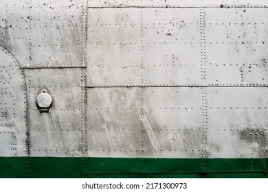 front view closeup of old airplane metallic hull fuselage plating with rows of bolts and rivets industrial texture