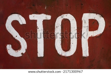 front view closeup of word stop written with white paint and capital letters brush typeface style on red rusted metallic plate texture