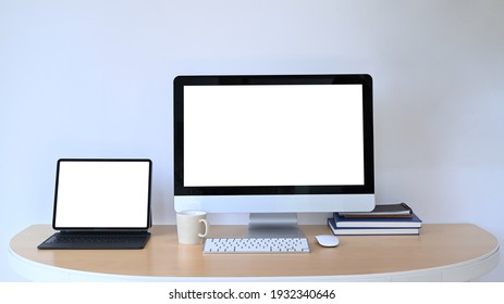 Front View Of Computer And Digital Tablet With Blank Screen On Wooden Office Desk.
