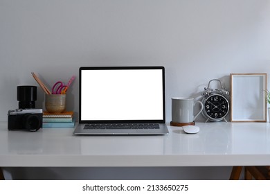 Front view computer laptop, stationery, alarm clock and picture frame on white table. - Powered by Shutterstock