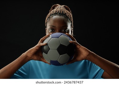 Front view concept shot of female football player holding ball and looking at camera with intense face expression - Powered by Shutterstock