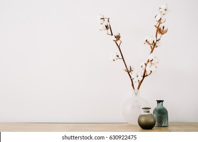 Front view of cotton branches and beauty stylish vase at white background. Minimalistic decorated home office desk. - Shutterstock ID 630922475