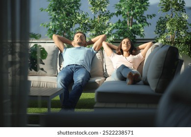 Front view of a couple relaxing on a couch in a terrace - Powered by Shutterstock