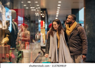 Front view of a couple walking past a shop window and looking in. They are shopping during the sales. - Powered by Shutterstock