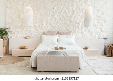 Front View Of Cozy Bed In Modern Bedroom With White Walls And Furniture Indoors. Minimalistic Interior Design Concept. Shot Of Spacious Light Room. Domestic Comfort. No People