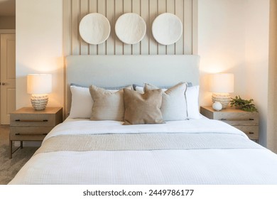 Front view of cozy double bed with stacked brown pillows, beige duvet in front of green paneled wall with copy space - Powered by Shutterstock