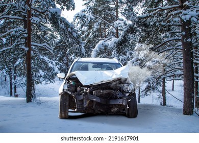 Front View Of A Crashed Car Wreck In Winter Forest Snow After The Accident With Smoke Coming Out From The Engine Under The Hood