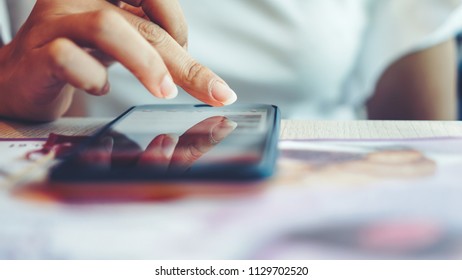 Front view of cropped young woman working on mobile while sitting in the restaurant. Close up hand of Woman using smartphone on the table - Shutterstock ID 1129702520