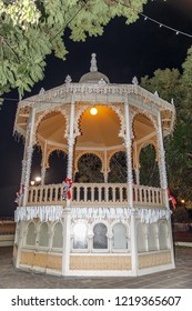 Front View Of A Cubicle In The Center Of A Square Decorated With Christmas Motifs And Lights, On A Beautiful Night