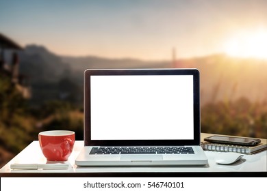 Front view of cup and laptop on table in Office Mountain and background of trees in the forest