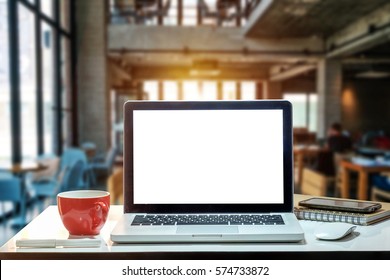 Front view of cup and laptop on table in office and background  in the coffee shop
				