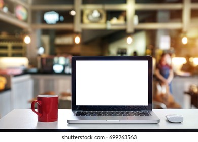 Front view of cup and laptop on table in office and background  in the coffee shop and restaurant
