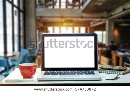 Front view of cup and laptop on table in office and background  in the coffee shop
