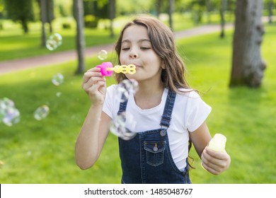 Front view cute little girl making soap bubbles