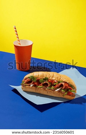 Front view of delicious bread with a orange disposable paper cup decorated on color paper background. Creative scene for advertising bread of Vietnamese with drinking. Copy space