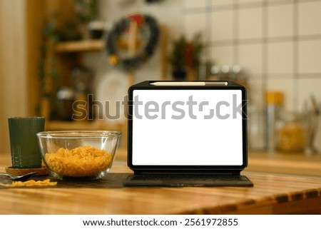 Front view digital tablet with white screen near a bowl of cornflakes on kitchen table