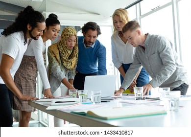 Front view of diverse business people working together on laptop at conference room in a modern office - Powered by Shutterstock