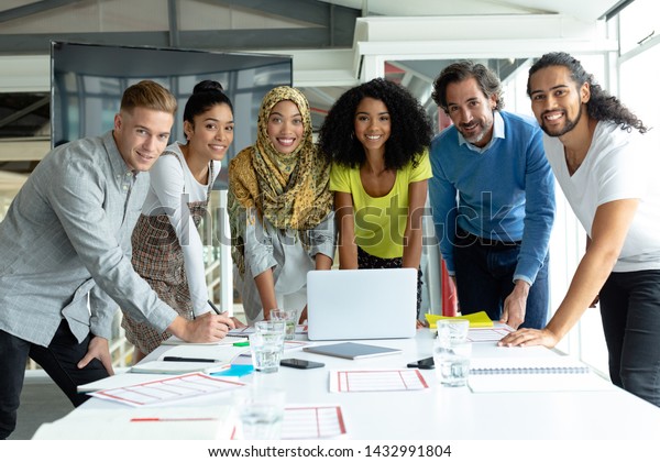 Front view\
of diverse business people looking at camera while working together\
at conference room in a modern\
office