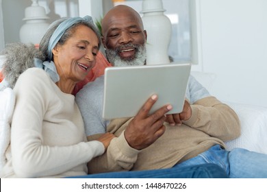 Front view of diverse senior couple using a digital tablet on sofa in beach house. Authentic Senior Retired Life Concept - Powered by Shutterstock