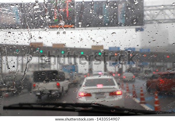 Front view of Driving with car\
windshield wipers in raining day on the expressway\
tollgate.
