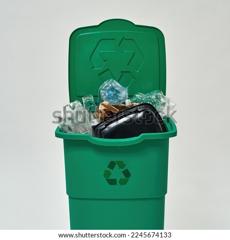 Front view of dustbin full of unsorted garbage. Ecology safety. Waste disposal and recycling. Environmental sustainability. Isolated on white background. Studio shoot