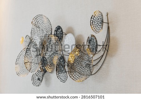 Front view of an elegant 3D abstract wall sculpture crafted from dark wire mesh disks and metallic gold circular elements mounted on a textured wall.