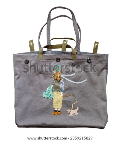 front view of empty handcrafted gray fabric tote bag with color girl and dog appliqued isolated on white background