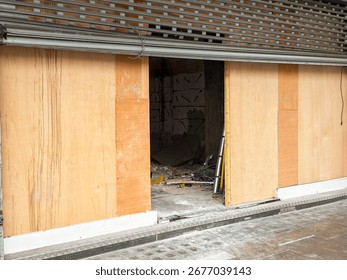 Front view of an empty shop in a high street being refurbished. No people.