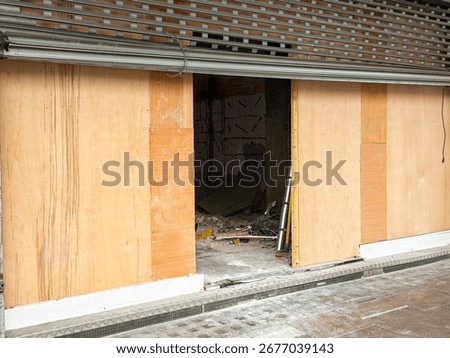 Front view of an empty shop in a high street being refurbished. No people.