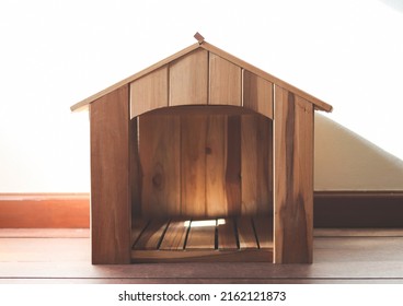 Front View Of Empty Wooden Dog House In The Room With Wooden Floor And White Wall And Morning Sunlight.