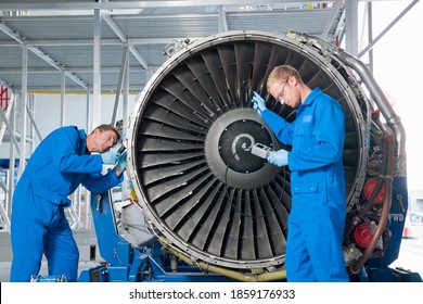 Front view of engineers inspecting the turbine engine of a passenger jet at a hangar. - Powered by Shutterstock