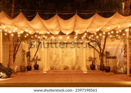 Front view of event or wedding stage at night with string lights and canopy. Background with copy space