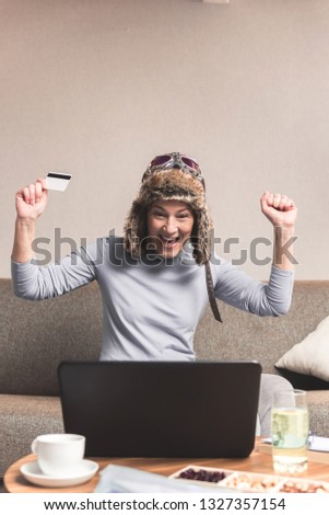 Front view of excited cheerful senior woman celebrating getting a loan from the bank, Online e-banking concept