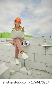 Front View Of A Female Construction Worker In A Safety Helmet Typing On A Computer